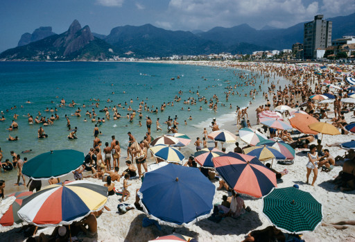 Umbrellas and swimmers dot Arpoador Beach.